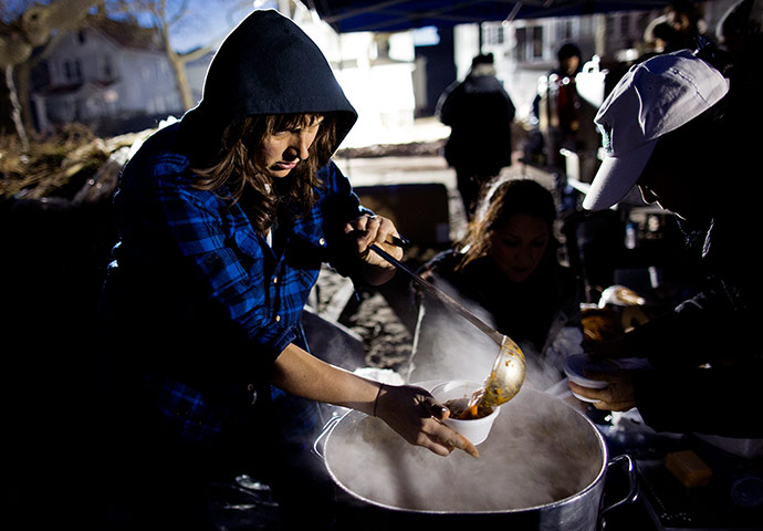 24 hours: New York, US: A woman ladles her food into a cup at make shift soup kitchen