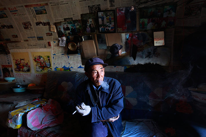 24 hours: Shaanxi Province, China: An apple farmer smokes in his home