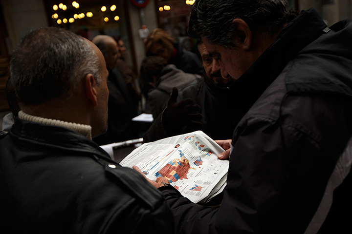 World election reaction: Madrid, Spain: People read a news paper with the US elections results 