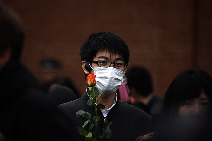 24 hours in pictures: A student from Japan in a mask holds a rose in Berlin