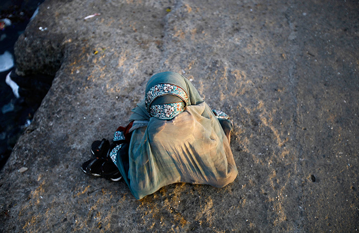 24 hours in pictures: A beggar girl hides her face in India