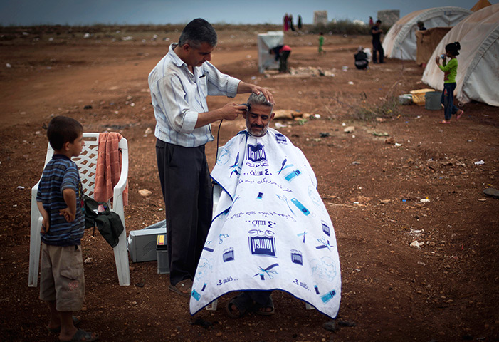 24 hours in pictures: A Syrian man sits for a haircut at a refugee camp near the Turkish border