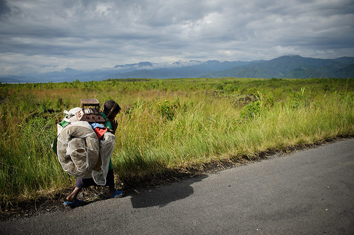 20 Photos: A displaced Congolese child carries her belongings back towards Sake