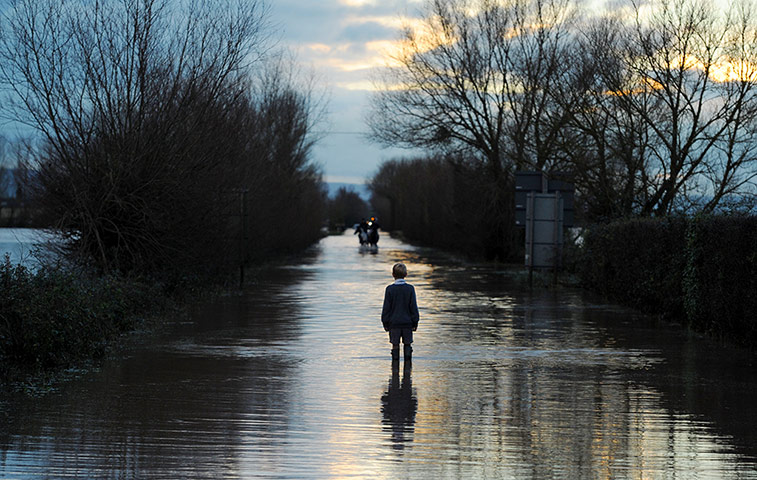 20 Photos: Autumn weather A boy watches horse riders on a flooded road in Somerset