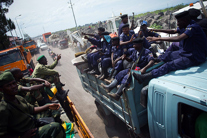 Goma: M23 rebels pass a truck of police officers as they withdraw from Goma 