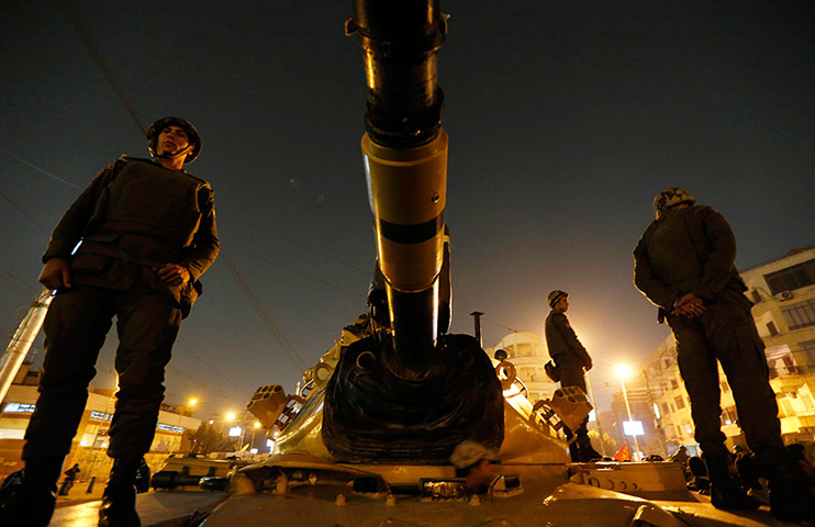 Egypt protests: Soldiers stand guard on top a tank in front of the presidential palace