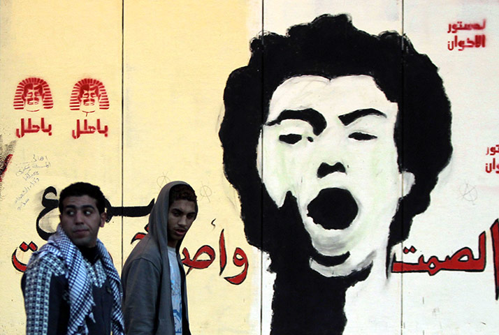 Egypt protests: Anti-Morsi protesters walk in front of a mural of activist Gaber Salah
