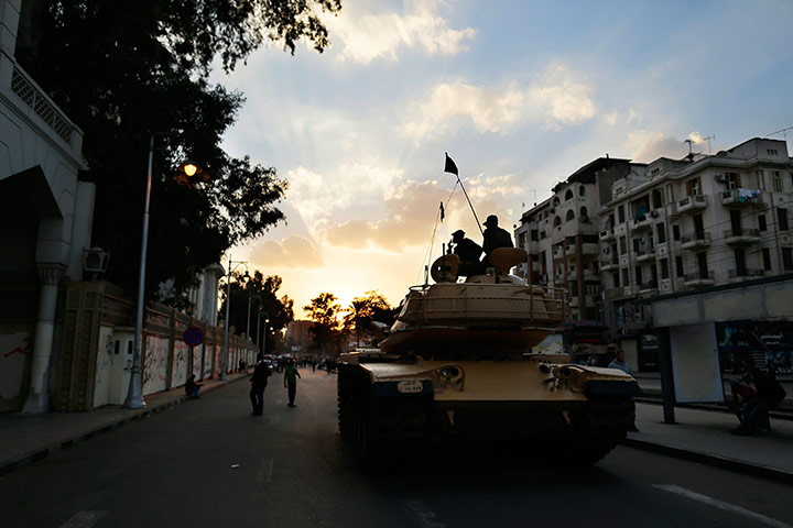 Egypt protests: Egyptian army soldiers sit on top of their tank as the sun sets in the city