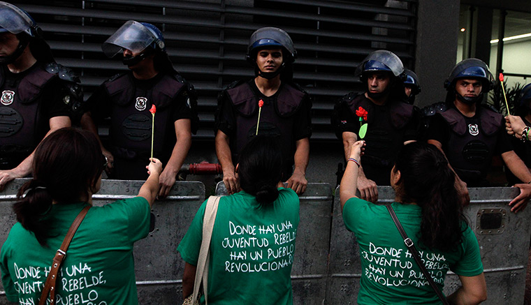 24 hours in pictures: ouths hand out flowers to riot police, Asuncion, Paraguay