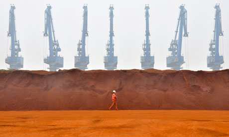 worker walking past a pile of iron ore 