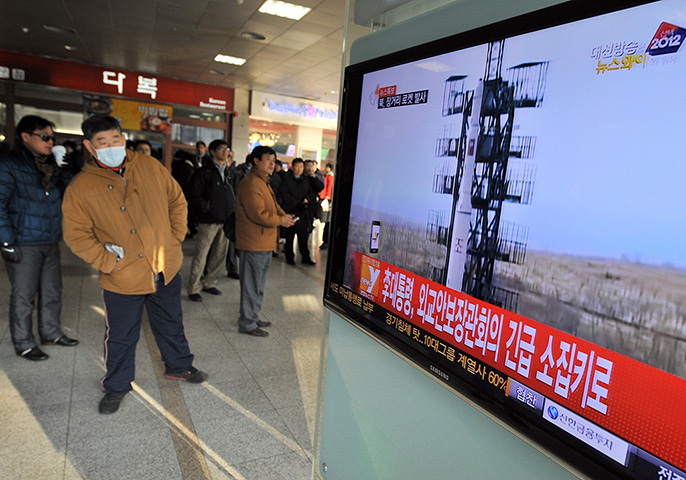 North Korea missile: Travellers watch a TV screen broadcasting news about rocket launch