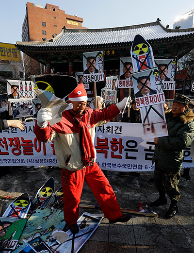 North Korea missile: A man wearing Santa Claus costume, tears a mock missile during a rally