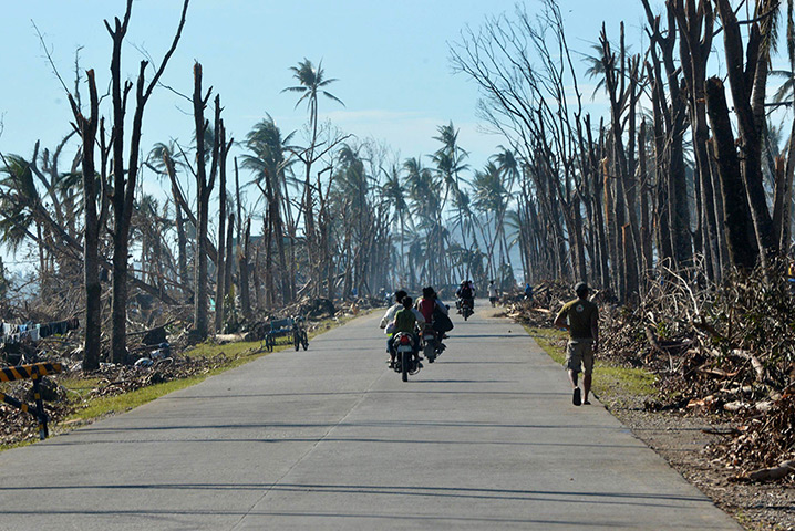 24 hours: Baganga, Philippines: Motorists ride past destroyed trees