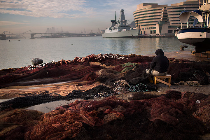 24 hours: Barcelona, Spain: A fisherman fixes his net at the fishing port 