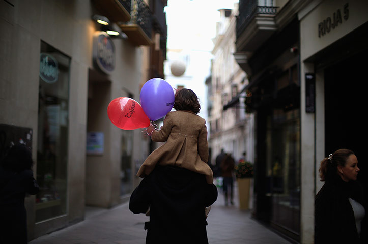 24 hours: Seville, Spain: A girl holds balloons as she sits on the shoulders of a man