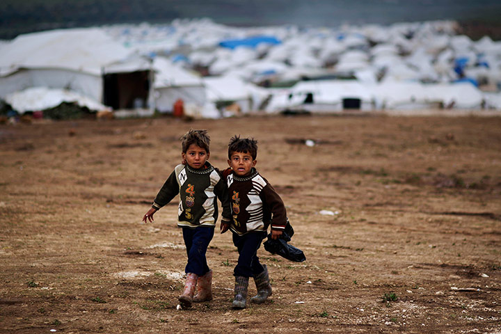 20 Photos: Two boys walk to their tent at a camp for displaced Syrians