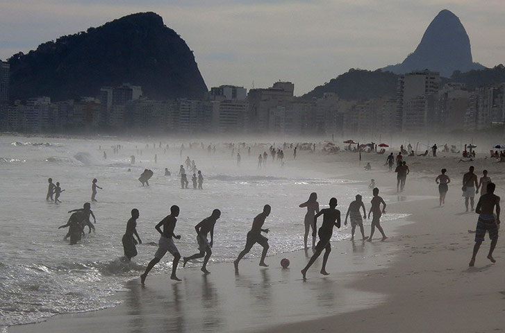 20 Photos: Boys play football at the edge of the surf at Copacabana Beach in Rio