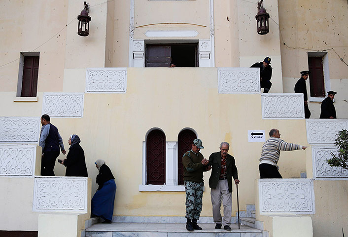 Egypt Referendum: An Egyptian soldier helps an elderly man after casting his vote