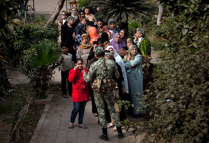 Egypt Referendum: An Egyptian soldier stands guard as voters wait outside a polling centre