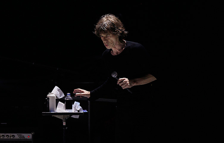 24 hours in pictures: Mick Jagger reaches for a bottle of water as he performs onstage