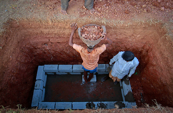 24 hours in pictures: Workers prepare to place clumps of mud inside a grave