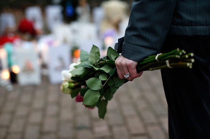 Sandy Hook: A woman clutches a bouquet of roses as she stands at a makeshift memorial