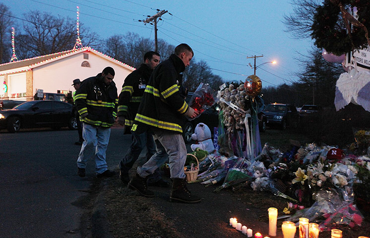 Sandy Hook: Firefighters pay their respects at a makeshift memorial near the school 