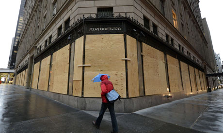 Woman walks past boarded up shops