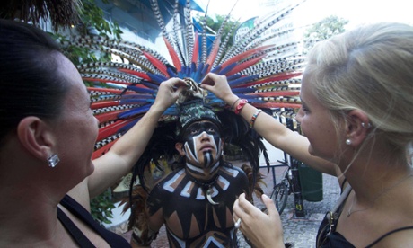German tourists interact with a Mexican man wearing a pre-hispanic costume at a tourist area of Playa del Carmen in Quintana Roo state, Mexico, during preparations for the celebration of the end of the Maya Long Count Calendar, Baktun 13, and the beginnig of a new era.