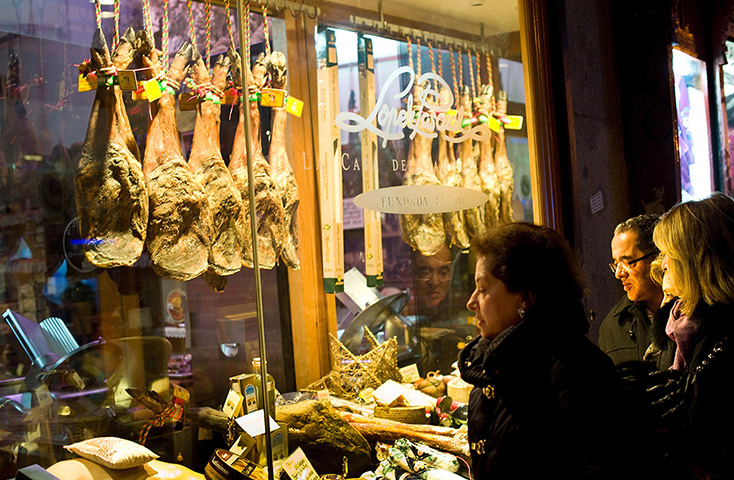 Pigs in Spain: Pedestrians look at the window display of Alberto Lopez Araque's jamon shop