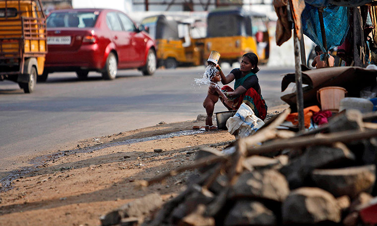 24 Hours: Hyderabad, India: A woman bathes her child on the side of a road