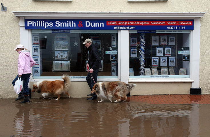 Wet weather: A couple walk their dogs past receding floodwater in the centre of Braunton