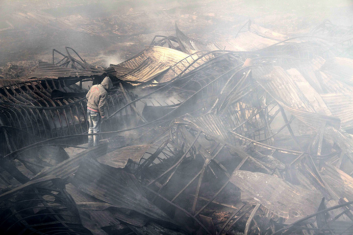 Kabul fire: A man stands in the still smouldering remains