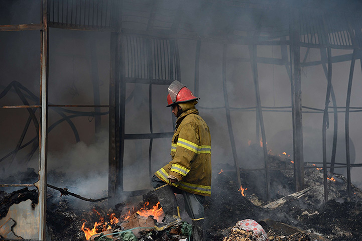 Kabul fire: An Afghan firefighter walks past smouldering shopfronts 