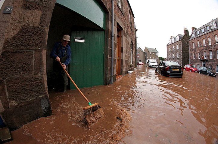 Uk flooding continues: Man sweeps the debris on the high street in  Stonehaven, near Aberdeen