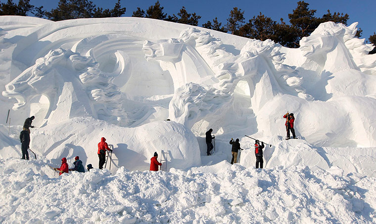 24 hours in pictures: Workers shape a snow sculpture
