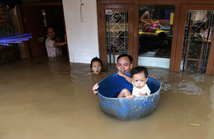 24 hours in pictures: A father holds a basin that his child sits in