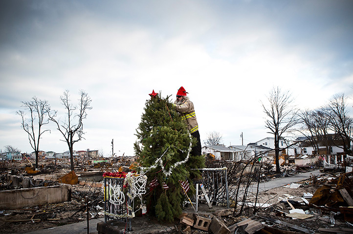 24 hours in pictures: Firefighter places a star on top of a Christmas Tree in the Breezy Point