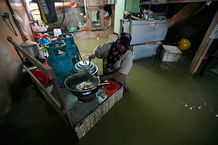 24 hours in pictures: A villager prepares food at her flooded house in Rantau Panjang