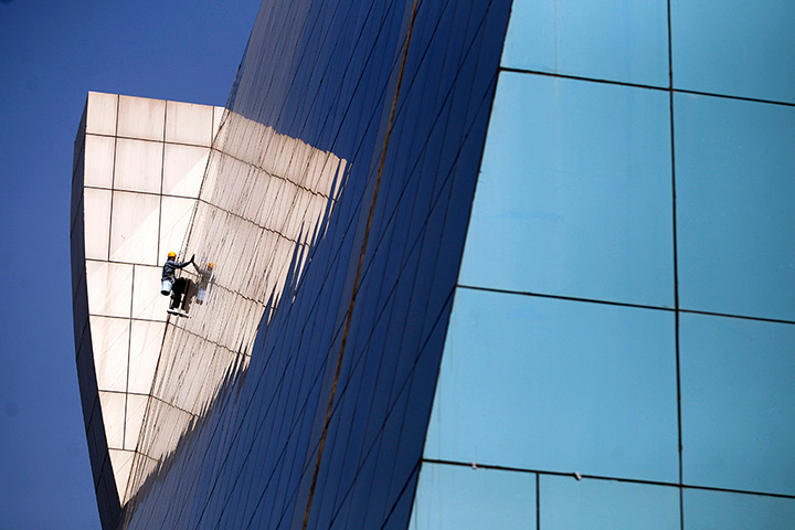 24 hours in pictures: An Indian worker cleans windows of a building