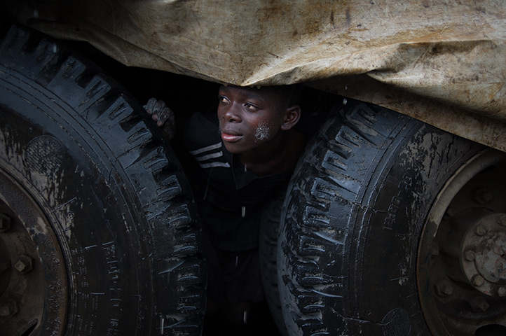 24 hours in pictures: An internally displaced Congolese boy shelters from the rain under a truck