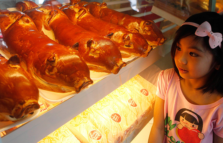 24 hours: Manila, Philippines: A girl looks at bread shaped like roasted pigs