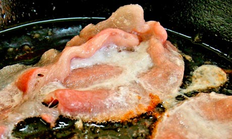 greasy bacon frying in a pan