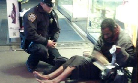 New York police officer Larry DePrimo gives a homeless man a pair of boots and socks in Times Square