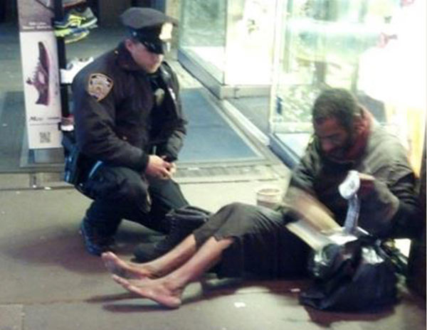 New York police officer Larry DePrimo gives a homeless man a pair of boots and socks in Times Square