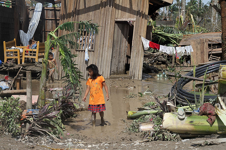 Typhoon Bopha: Children walk in front of their flooded home