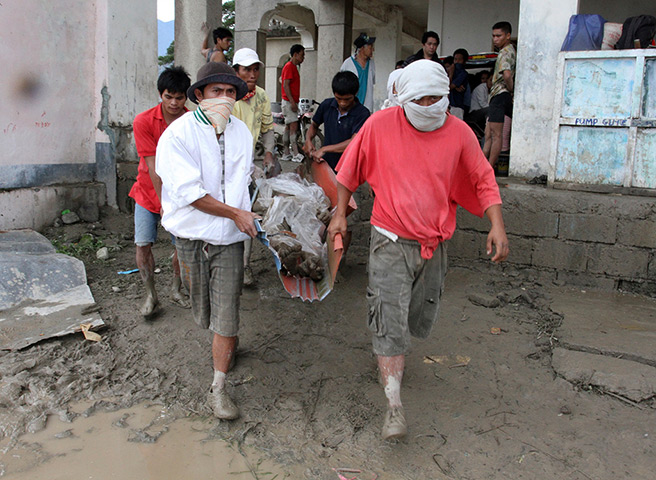 Typhoon Bopha: Rescuers carry a flash flood victim from New Bataan 