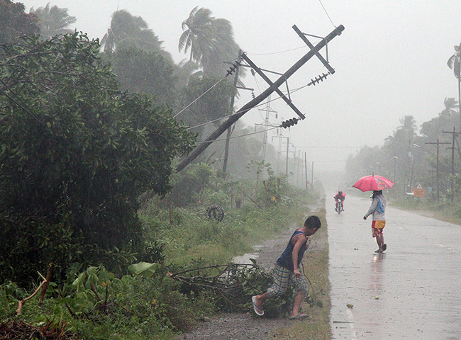 Typhoon Bopha: Residents brave heavy rains next to a tilted electric post in Tagum