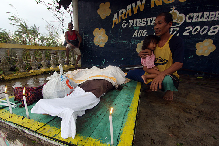 Typhoon Bopha: A man looks at the bodies of relatives killed by landslides