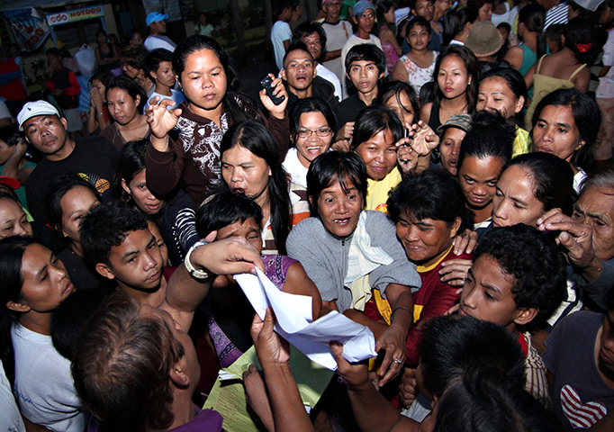 Typhoon Bopha: Residents gather to check the list of supplies at an evacuation centre 